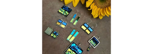 Blue and yellow earrings and pendants representing the flag of Ukraine. Silver and gold jewelry with brilliant dichroic glass on flagstone with sunflowers